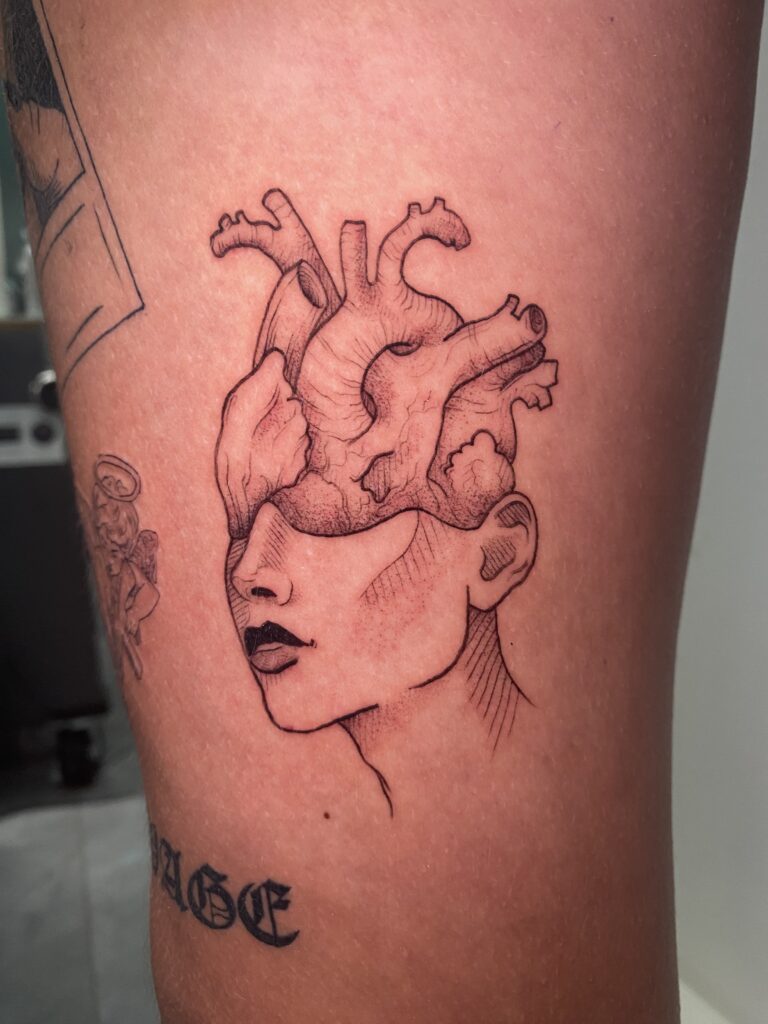 Tattoo eines Kopfes mit einem Herz im Kopf, gestaltet von Resident Tattoo-Künstlerin Basja.