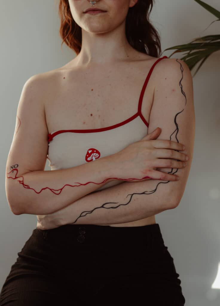 Linien-Tattoo in Schwarz und Rot auf den Armen von Ricarda im Atelier Noir nu Köln Ehrenfeld